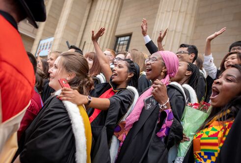 A crowd of students celebrating on the steps of the Caird Hall after the graduation ceremony