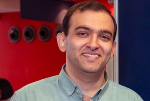 Abdullah Alagha, wearing a green-collared shirt, smiling