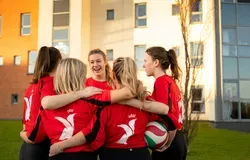University of Dundee Women's volleyball team in a group huddle.
