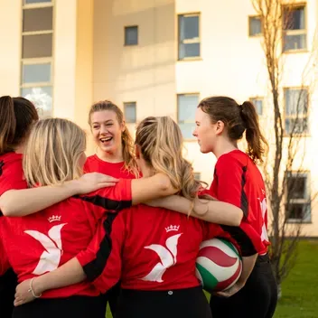 University of Dundee Women's volleyball team in a group huddle.