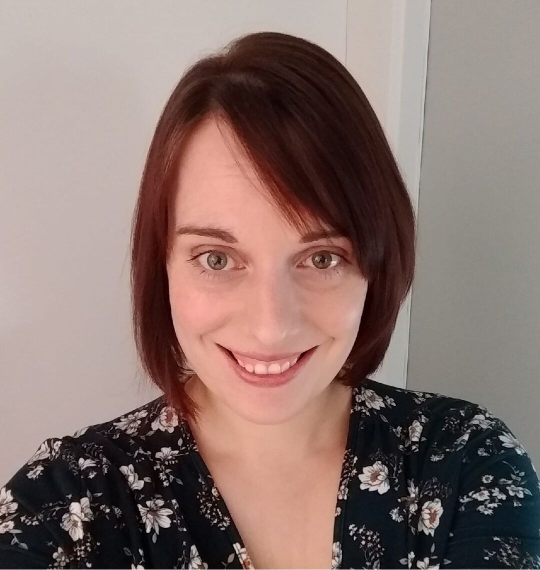 close up photograph of woman with short dark hair looking at the camera and smiling